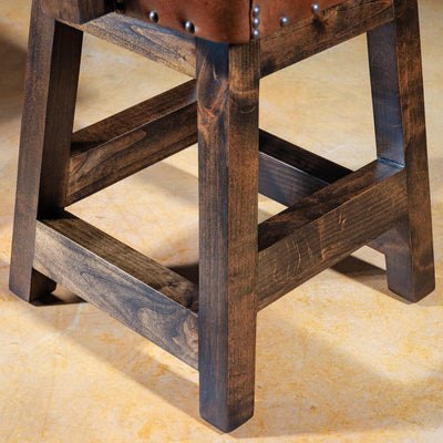 Close-up of solid wood legs on a brown Western bar stool with rustic detailing