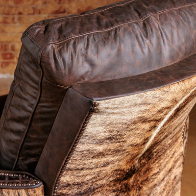 Close-up of brindle cowhide and antique nailhead detailing on leather recliner