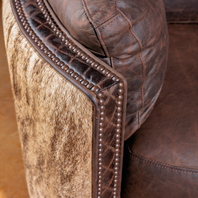 Close-up of brindle cowhide and antique nailhead detailing on leather recliner