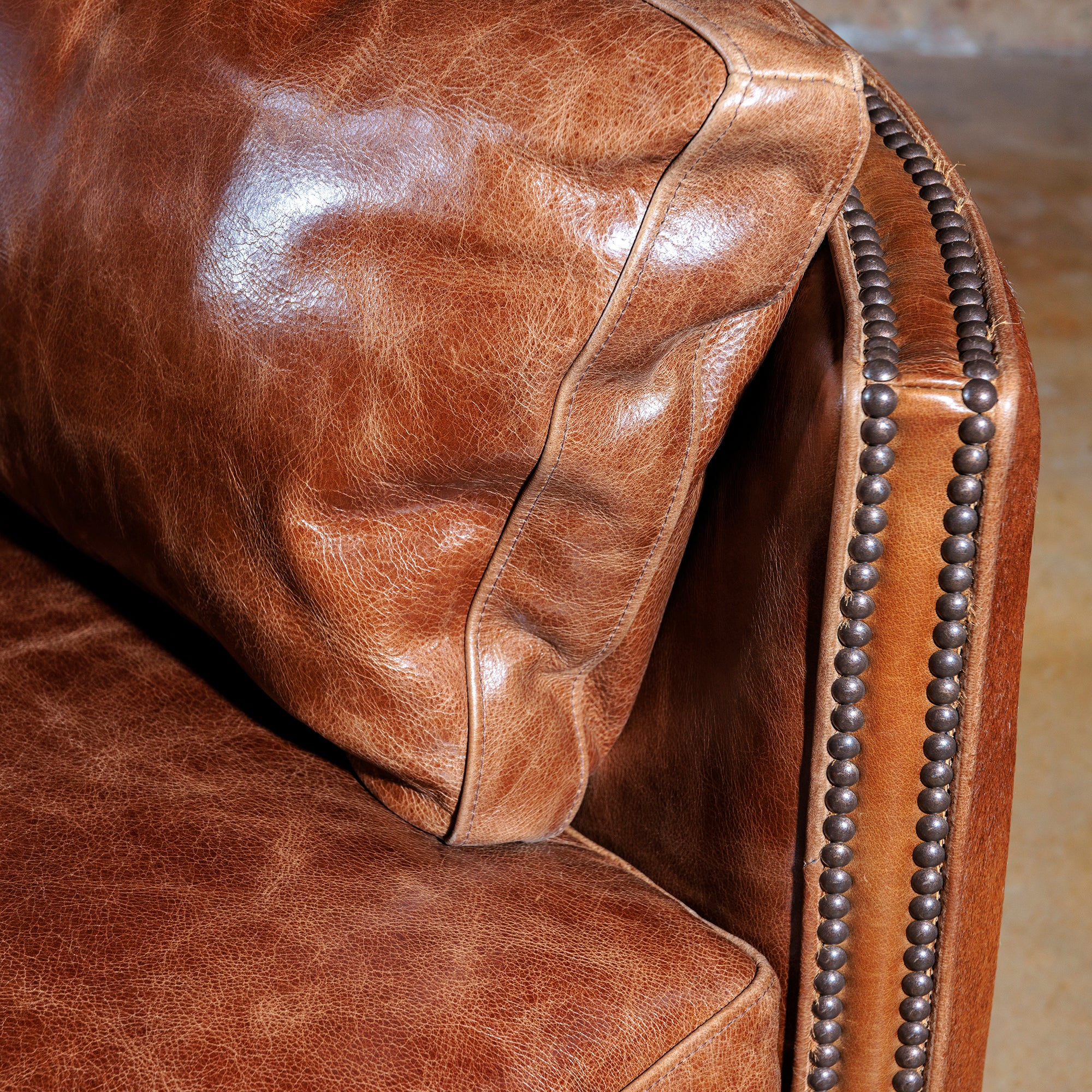 Close-up of rustic nailhead trim, brindle cowhide, and premium leather on handcrafted Western recliner