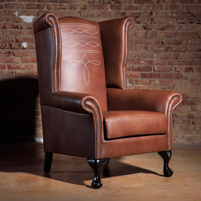 Western leather wingback chair front view with cowboy stitch detailing and nailhead trim